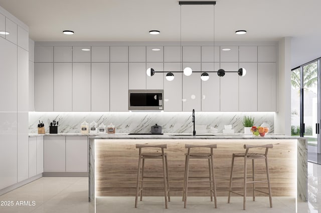 bar with sink, backsplash, light tile patterned floors, and white cabinets