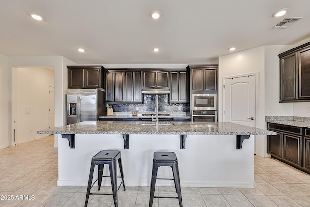 19946 W Glenrosa Ave, Litchfield Park, AZ 85340 - kitchen featuring visible vents, a breakfast bar, light stone counters, light tile patterned floors, and stainless steel appliances