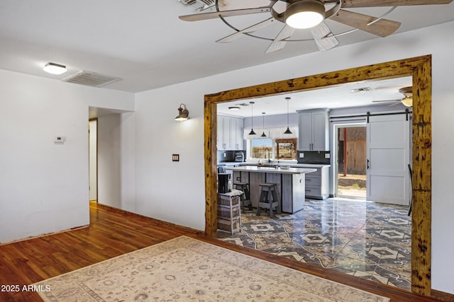 2921 N 103rd Ave, Avondale, AZ 85392 - kitchen with a barn door, a ceiling fan, a breakfast bar area, a center island, and light countertops