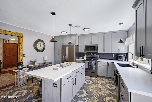 2921 N 103rd Ave, Avondale, AZ 85392 - kitchen with stainless steel appliances, gray cabinets, light countertops, decorative backsplash, and a kitchen island