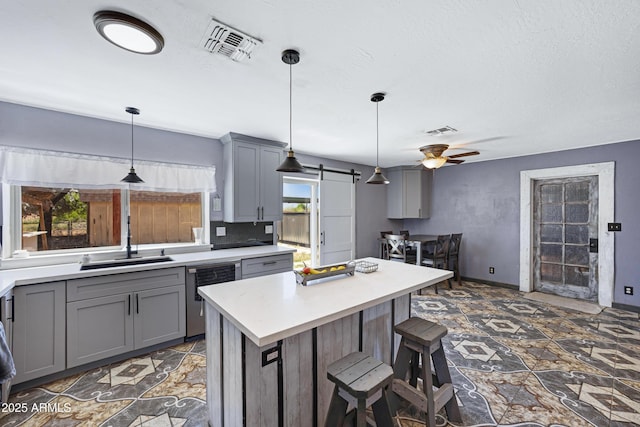2921 N 103rd Ave, Avondale, AZ 85392 - kitchen featuring dishwasher, gray cabinets, a barn door, ceiling fan, and light countertops