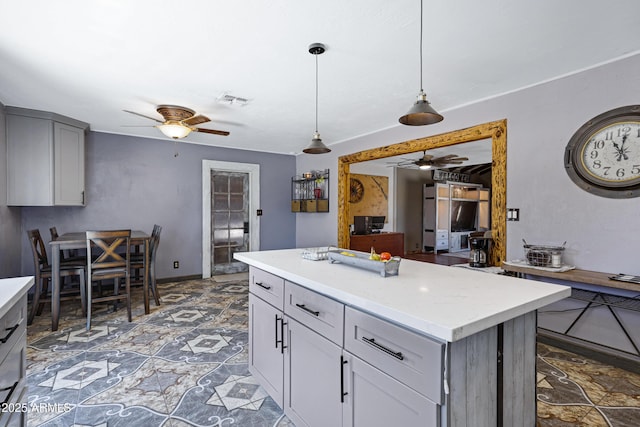 2921 N 103rd Ave, Avondale, AZ 85392 - kitchen featuring ceiling fan, light countertops, decorative light fixtures, gray cabinetry, and a kitchen island