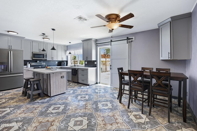 2921 N 103rd Ave, Avondale, AZ 85392 - kitchen featuring appliances with stainless steel finishes, gray cabinetry, a barn door, a ceiling fan, and light countertops