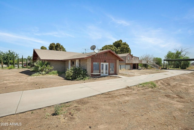 2921 N 103rd Ave, Avondale, AZ 85392 - view of front facade featuring french doors, board and batten siding, brick siding, and stairs