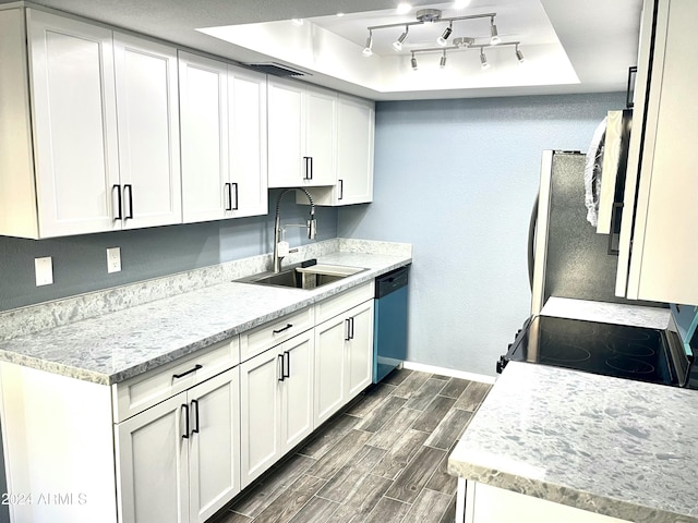 kitchen with a raised ceiling, sink, light stone countertops, white cabinetry, and stainless steel appliances