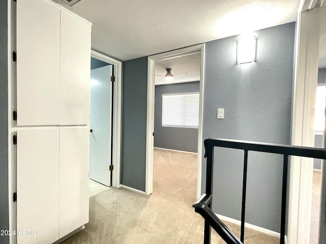 corridor featuring light carpet and a textured ceiling