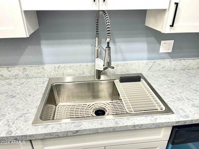 room details featuring light stone counters, white cabinetry, and sink