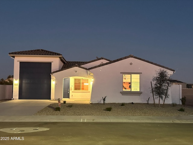 mediterranean / spanish-style house featuring a tile roof, a garage, driveway, and stucco siding