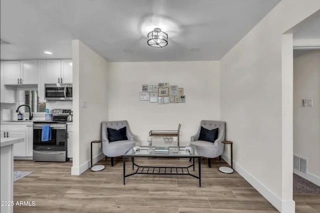 sitting room with sink and light hardwood / wood-style floors