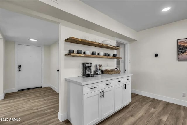 bar featuring light hardwood / wood-style floors and white cabinetry