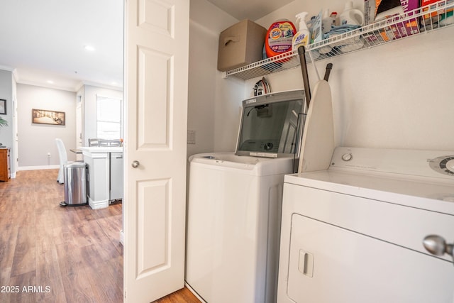 laundry area with washing machine and clothes dryer, crown molding, laundry area, light wood-style flooring, and baseboards
