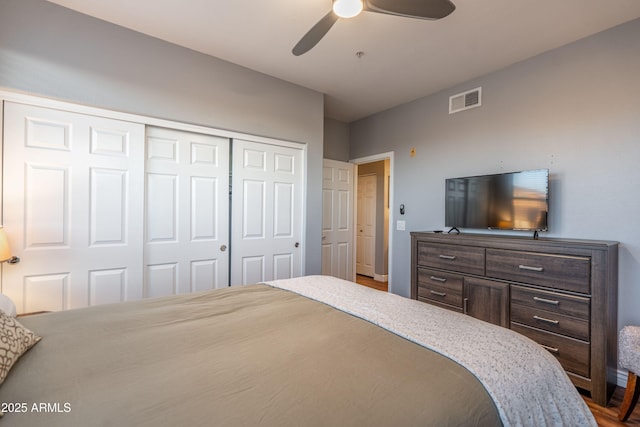 bedroom with ceiling fan, a closet, wood finished floors, and visible vents