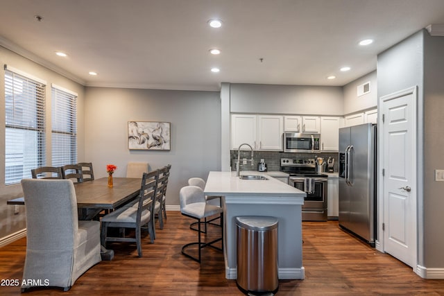 kitchen featuring a peninsula, a breakfast bar, white cabinetry, a sink, and appliances with stainless steel finishes