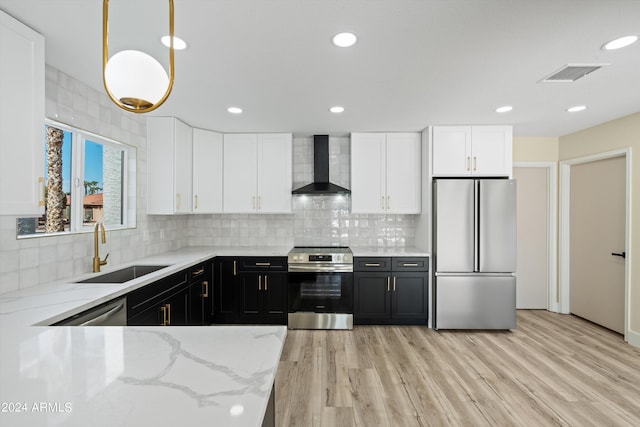 kitchen featuring light hardwood / wood-style floors, sink, hanging light fixtures, wall chimney range hood, and stainless steel appliances