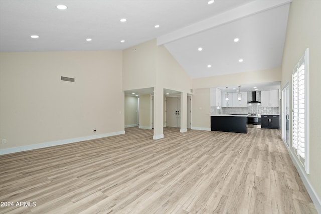 unfurnished living room with light hardwood / wood-style flooring, a wealth of natural light, high vaulted ceiling, and sink