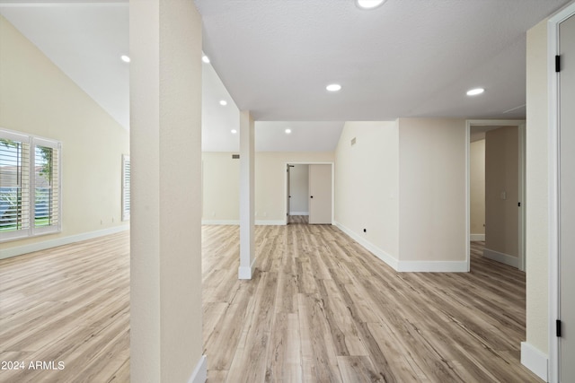 hallway with light hardwood / wood-style floors and vaulted ceiling