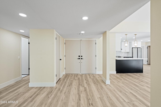 foyer entrance featuring a textured ceiling and light wood-type flooring