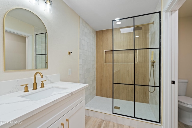 bathroom featuring a shower with door, toilet, vanity, and hardwood / wood-style flooring