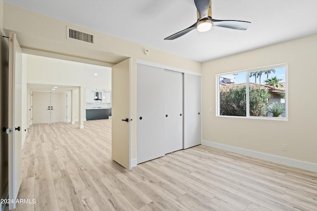 unfurnished bedroom with light wood-type flooring, ceiling fan, and a closet