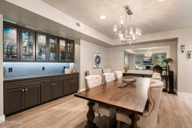 dining area with light wood-type flooring and a notable chandelier