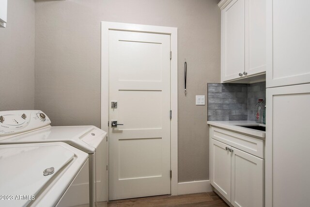 laundry area with independent washer and dryer, dark hardwood / wood-style floors, cabinets, and sink