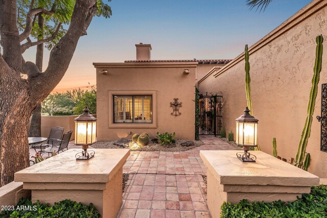 back house at dusk featuring a patio area