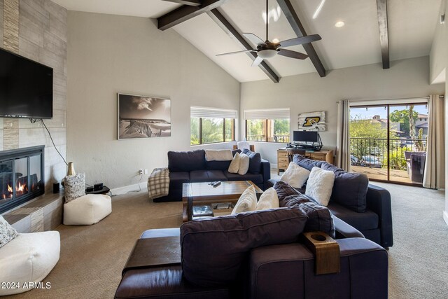 carpeted living room with high vaulted ceiling, ceiling fan, a tile fireplace, and beam ceiling