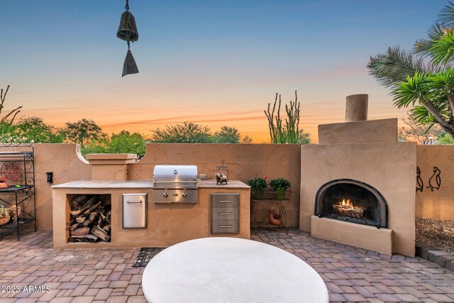 patio terrace at dusk with grilling area and an outdoor kitchen