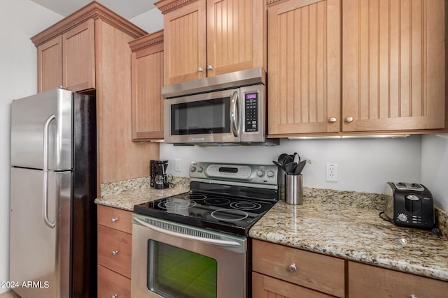 kitchen featuring appliances with stainless steel finishes, light stone countertops, and light brown cabinets