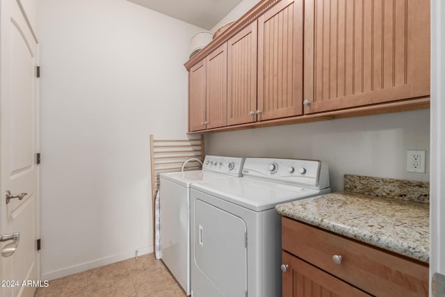 laundry area with washing machine and dryer, light tile patterned floors, and cabinets