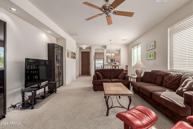 living room with light colored carpet and ceiling fan with notable chandelier