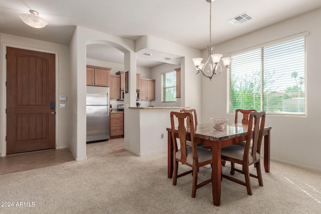 dining room featuring light colored carpet, a notable chandelier, and a wealth of natural light