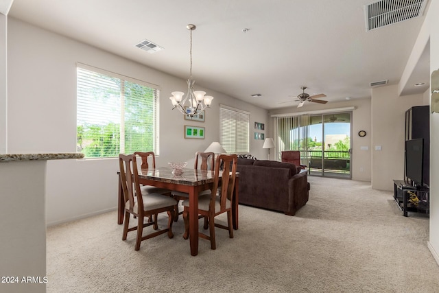 carpeted dining room with ceiling fan with notable chandelier