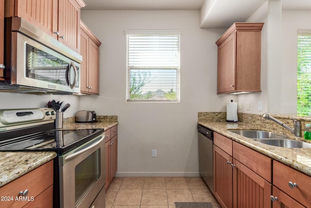 kitchen with sink, stainless steel appliances, light stone countertops, and light tile patterned floors