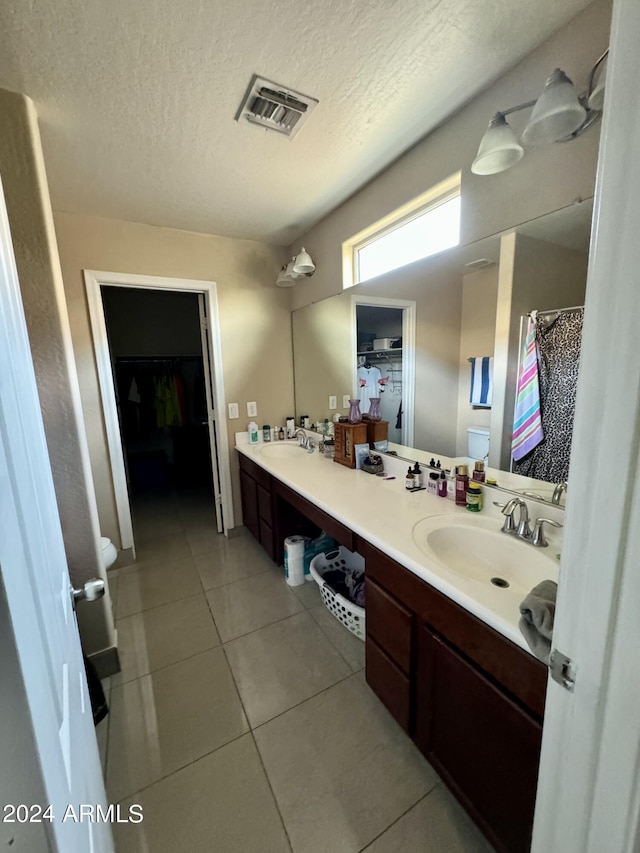 bathroom featuring vanity, a textured ceiling, tile patterned floors, and toilet