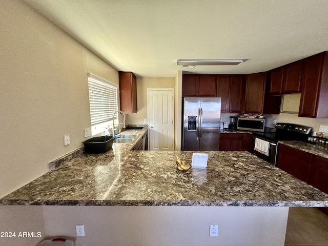 kitchen featuring appliances with stainless steel finishes, kitchen peninsula, sink, and dark stone countertops