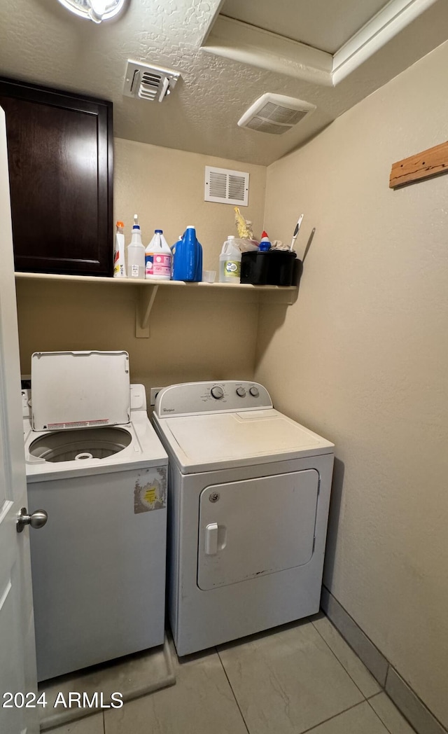 laundry room featuring separate washer and dryer, cabinets, and a textured ceiling