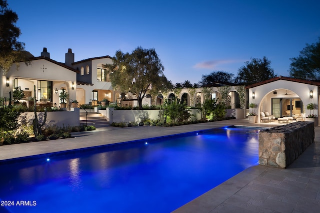 pool at dusk featuring a patio