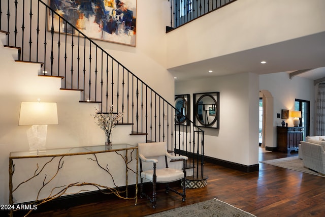 stairway featuring wood-type flooring and a high ceiling