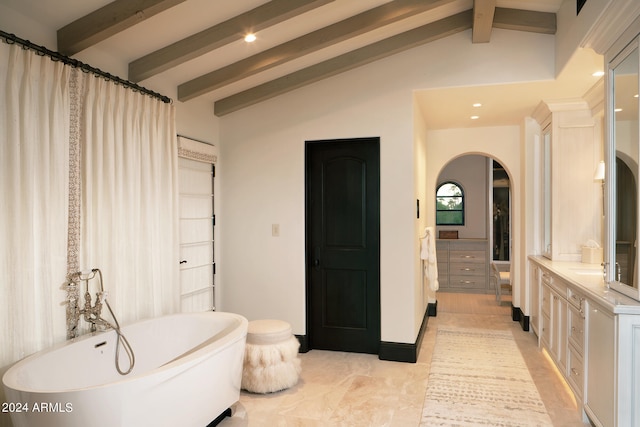 bathroom featuring a bath, lofted ceiling with beams, and vanity