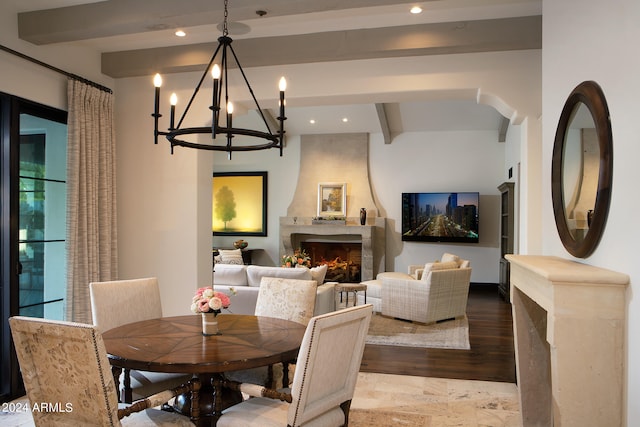 dining space featuring hardwood / wood-style floors, beamed ceiling, and a large fireplace