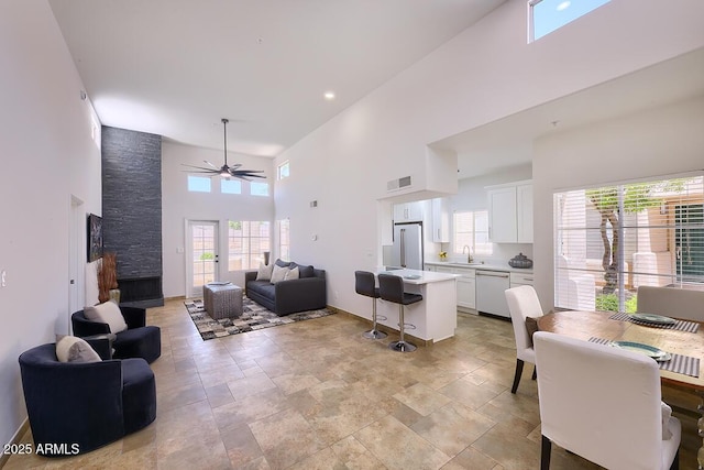 11333 N 92nd St Unit 1118, Scottsdale, AZ 85260 - living area featuring a high ceiling, ceiling fan, light stone finish flooring, plenty of natural light, and a stone fireplace