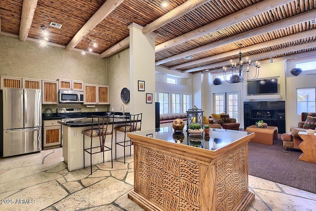 11333 N 92nd St Unit 1118, Scottsdale, AZ 85260 - kitchen with appliances with stainless steel finishes, open floor plan, a kitchen breakfast bar, healthy amount of natural light, and a wood ceiling with exposed beams