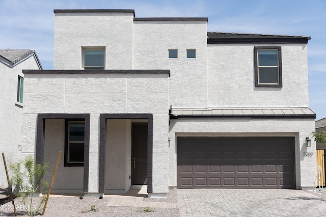 view of front of property featuring stucco siding, decorative driveway, and a garage