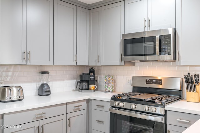 kitchen with appliances with stainless steel finishes, decorative backsplash, and gray cabinetry