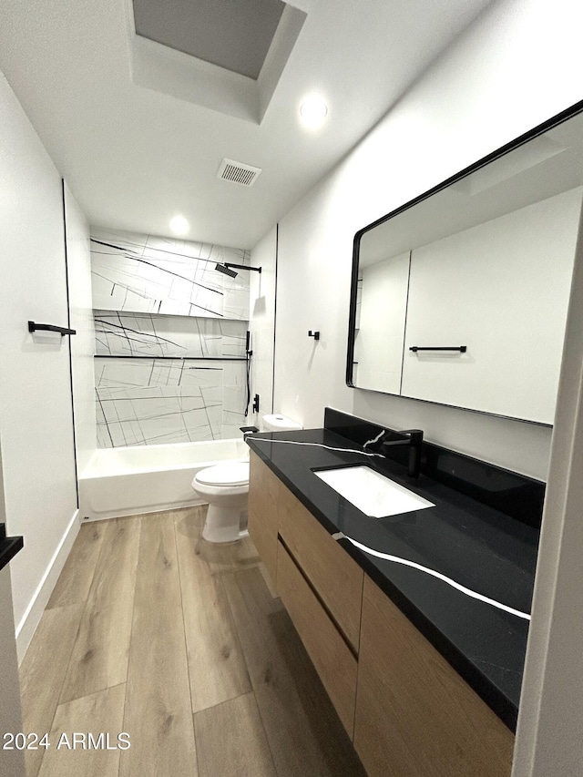 full bathroom featuring hardwood / wood-style flooring, vanity, toilet, and tiled shower / bath combo