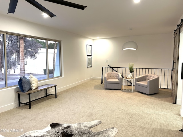 living area featuring a barn door and light carpet