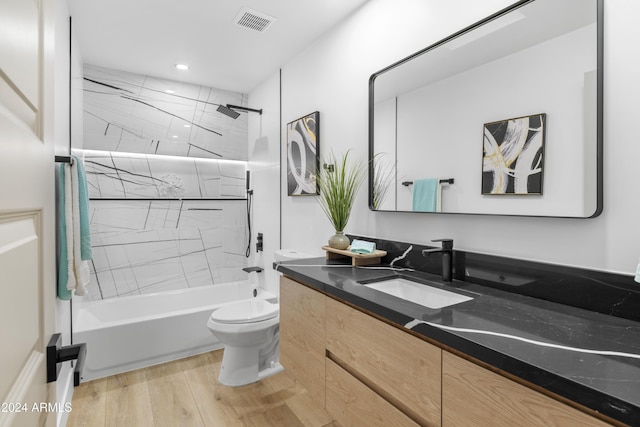 full bathroom with vanity, hardwood / wood-style flooring, toilet, and tiled shower / bath combo