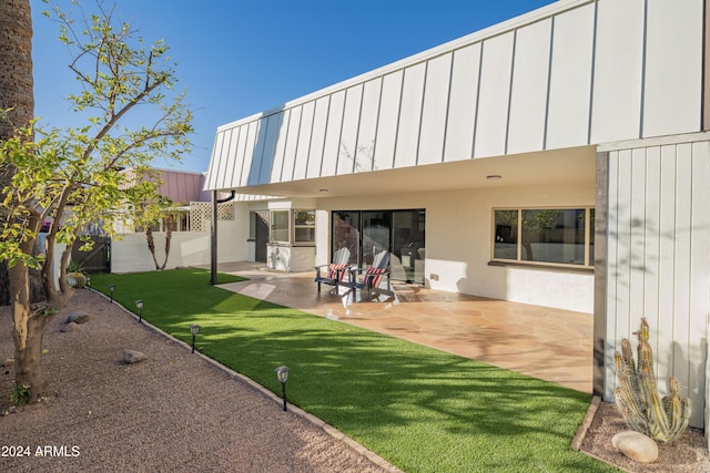 back of property featuring a patio area and a lawn