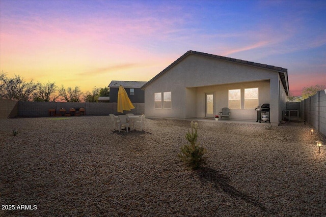 back house at dusk featuring a patio